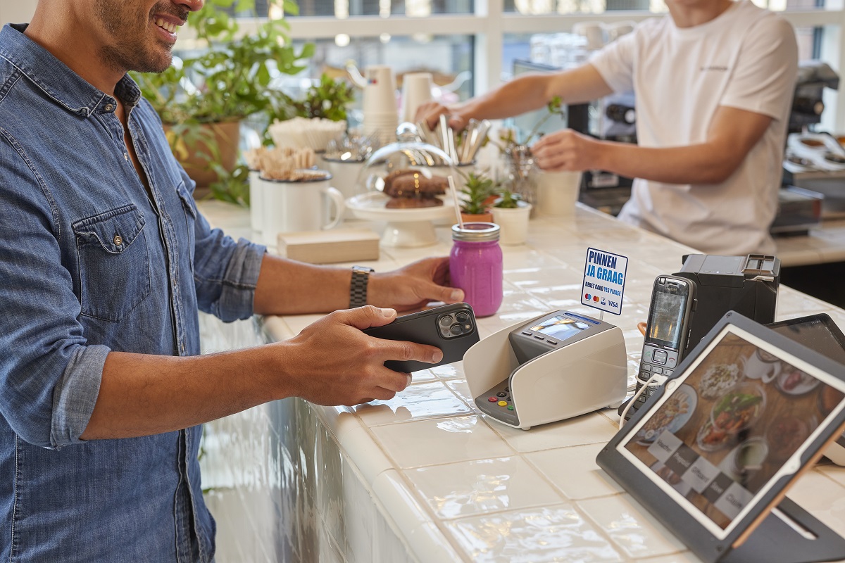 Klant voert mobiele betaling uit bij een betaalterminal in een café.